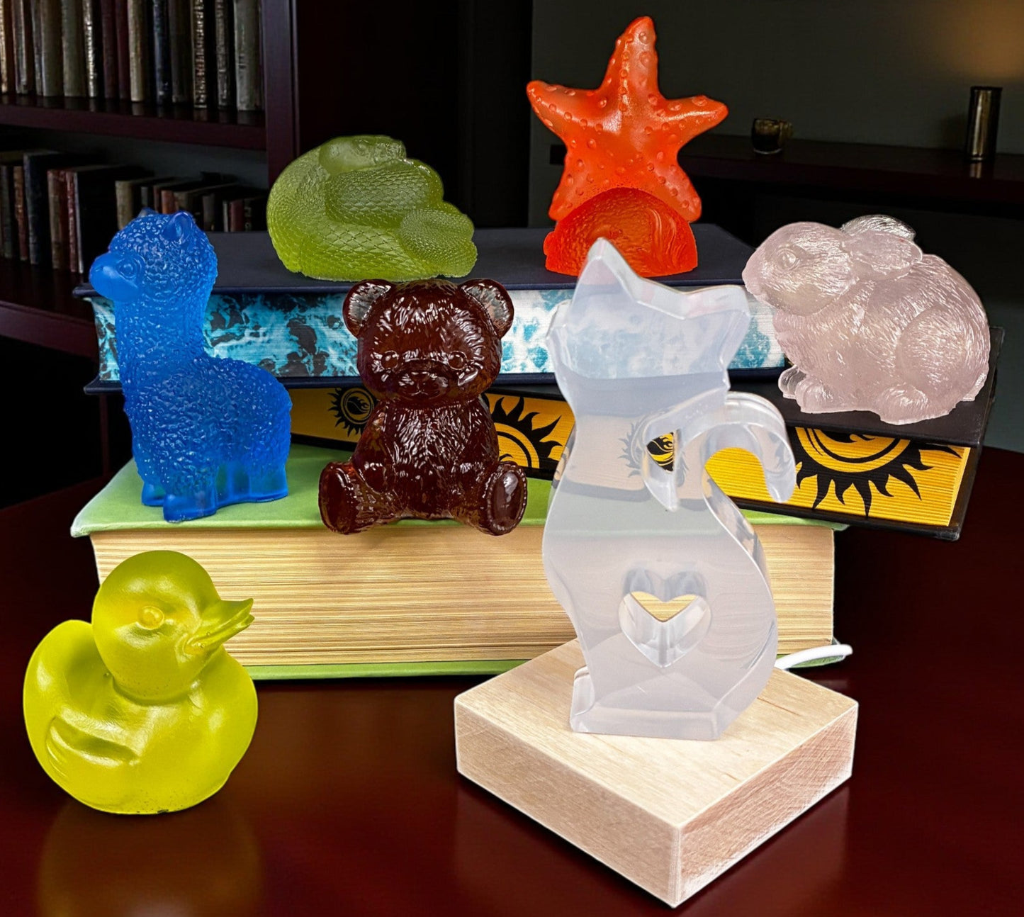 Colorful glass animal figurines on a wooden surface with books in the background