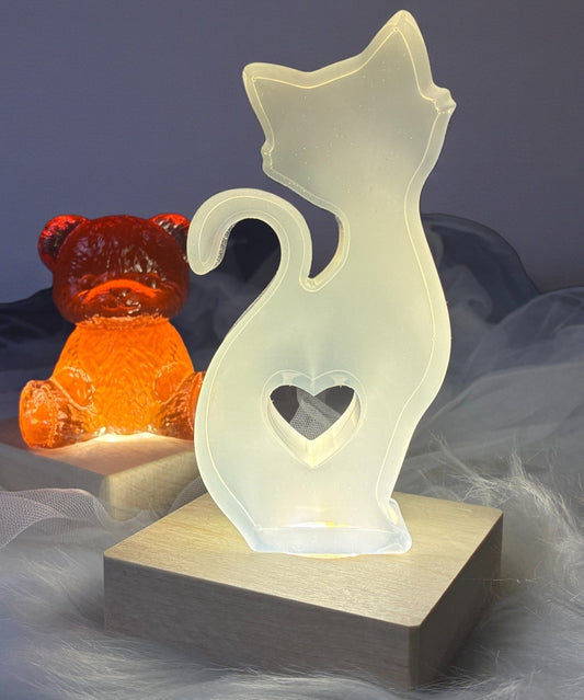 Two decorative lights shaped like a bear and a cat with a heart on a soft, gray background.